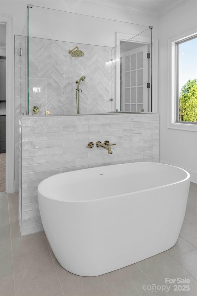 full bath featuring tile patterned flooring, ornamental molding, a freestanding bath, and a tile shower