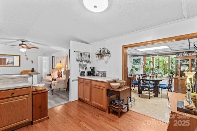 3755 River Rd, Richfield, NC 28137 - kitchen featuring ceiling fan, brown cabinets, light wood-style flooring, light countertops, and a textured ceiling