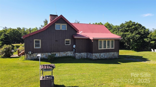 view of side of home with a yard, a chimney, and metal roof