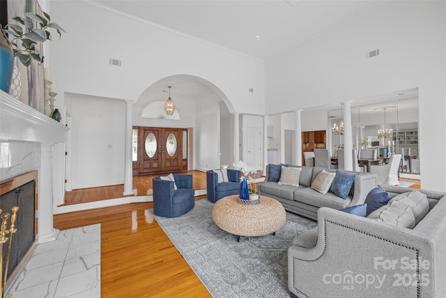 16108 Woolwine Rd, Charlotte, NC 28278 - living area with ornate columns, a towering ceiling, arched walkways, a premium fireplace, and wood finished floors