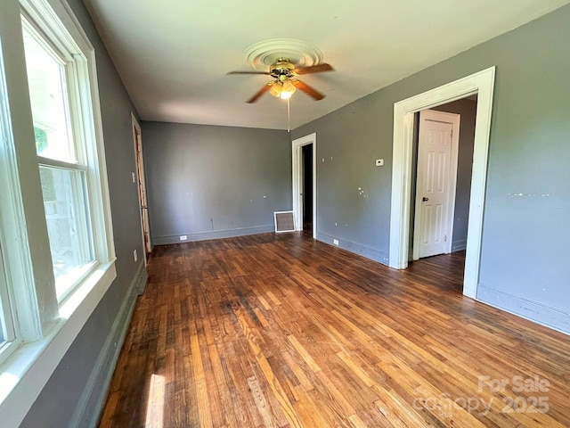 empty room with ceiling fan, hardwood / wood-style floors, a healthy amount of sunlight, and visible vents
