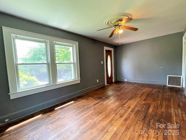 spare room with baseboards, visible vents, wood finished floors, and a ceiling fan