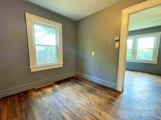 empty room with baseboards, hardwood / wood-style floors, and a healthy amount of sunlight