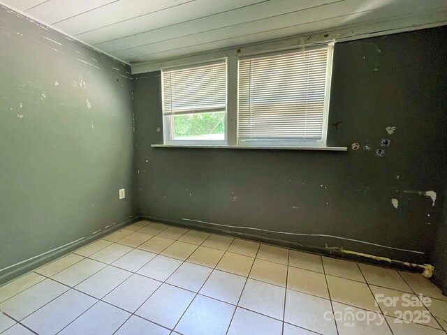 tiled spare room featuring baseboards