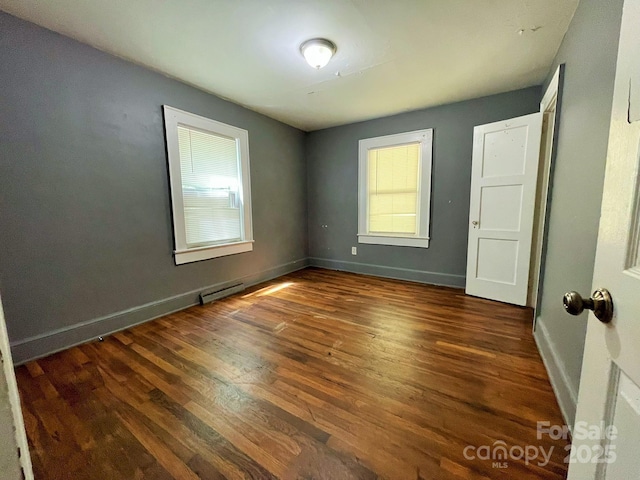 empty room featuring baseboards, wood finished floors, and baseboard heating
