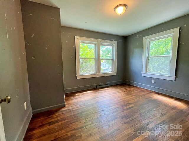 spare room with baseboards, a healthy amount of sunlight, and wood finished floors