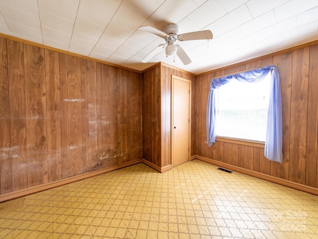 1470 Hilltop St, Albemarle, NC 28001 - unfurnished room featuring visible vents, tile patterned floors, wooden walls, a ceiling fan, and baseboards