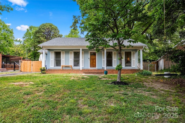 view of front of house with brick siding, a porch, fence, and a front yard