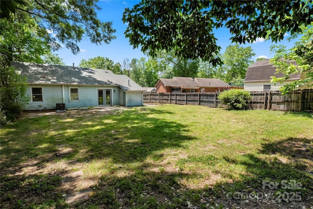 view of yard featuring french doors, a fenced backyard, and central AC