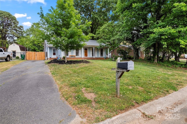 view of front of home with covered porch, a gate, fence, aphalt driveway, and a front yard
