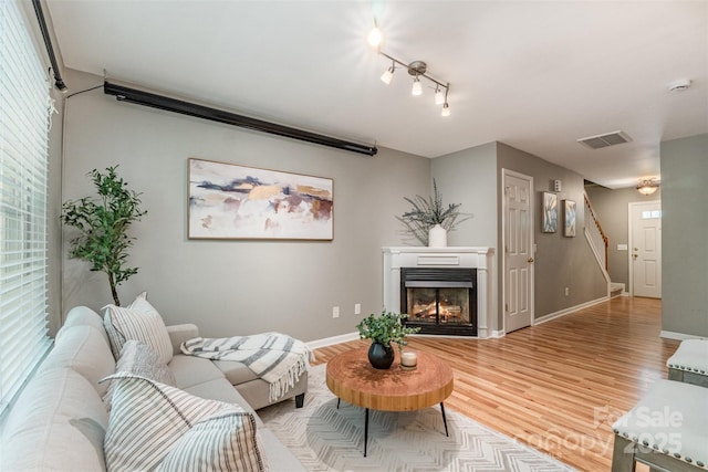 10421 Columbia Crest Ct, Charlotte, NC 28270 - living room featuring wood finished floors, stairway, and a warm lit fireplace
