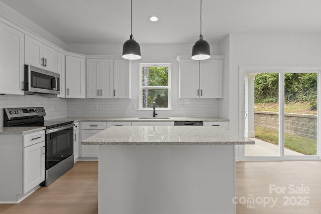 518 Herms Ave, Mount Holly, NC 28120 - kitchen with stainless steel appliances, a sink, light wood finished floors, tasteful backsplash, and a kitchen island