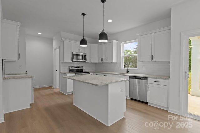 518 Herms Ave, Mount Holly, NC 28120 - kitchen featuring stainless steel appliances, a sink, light wood-style flooring, decorative backsplash, and white cabinetry
