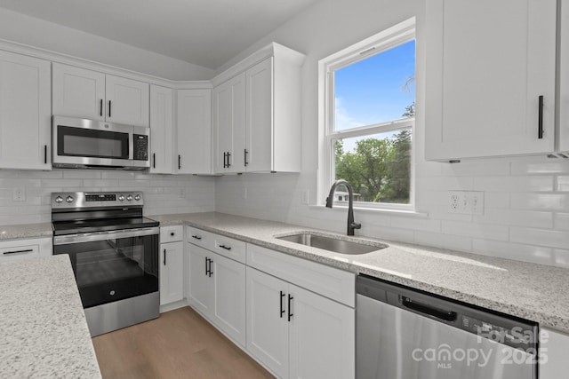 518 Herms Ave, Mount Holly, NC 28120 - kitchen with stainless steel appliances, a sink, white cabinetry, light wood-type flooring, and tasteful backsplash