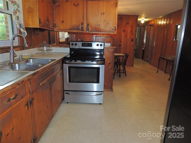 kitchen featuring a sink, brown cabinets, light countertops, and electric range
