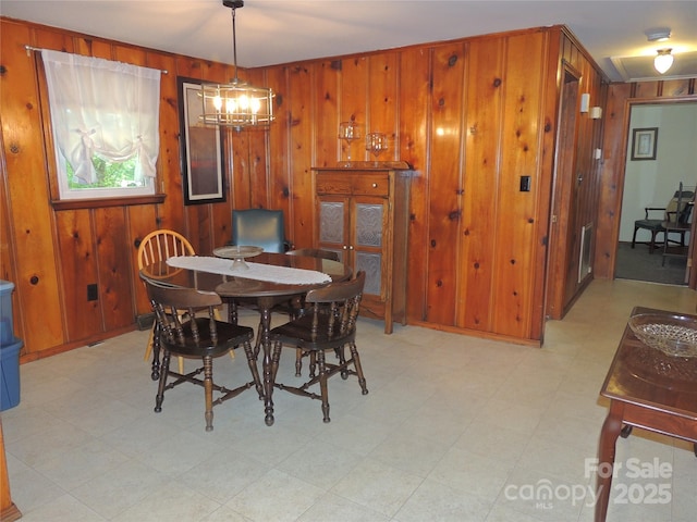 dining space featuring a chandelier, light floors, and wooden walls