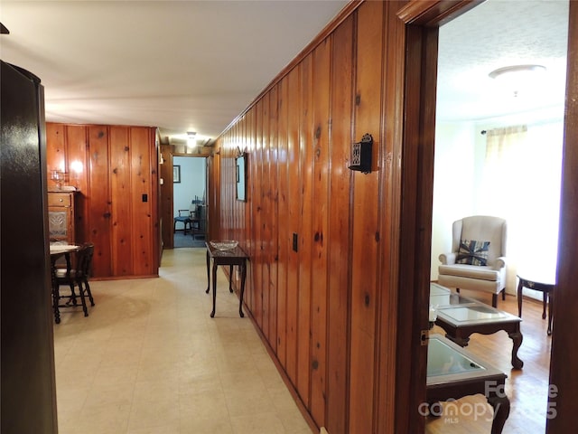 hall featuring light floors and wood walls