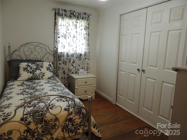 bedroom with a closet, dark wood-type flooring, and baseboards