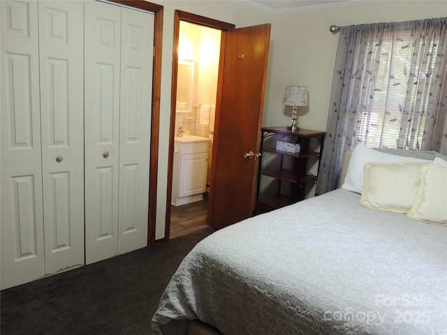 bedroom featuring crown molding, dark colored carpet, connected bathroom, and a closet