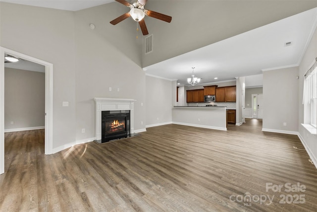 8505 Loxton Cir, Charlotte, NC 28214 - unfurnished living room featuring dark wood-style flooring, ceiling fan with notable chandelier, baseboards, and a glass covered fireplace