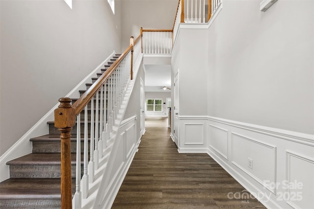 8505 Loxton Cir, Charlotte, NC 28214 - staircase with a decorative wall, wood finished floors, a ceiling fan, wainscoting, and a high ceiling