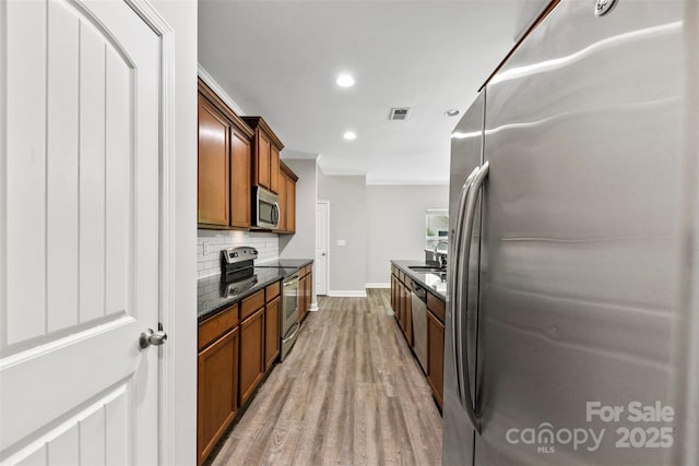 8505 Loxton Cir, Charlotte, NC 28214 - kitchen with brown cabinetry, visible vents, backsplash, light wood-style floors, and stainless steel appliances