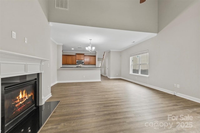 8505 Loxton Cir, Charlotte, NC 28214 - unfurnished living room featuring an inviting chandelier, wood finished floors, a fireplace with flush hearth, visible vents, and baseboards