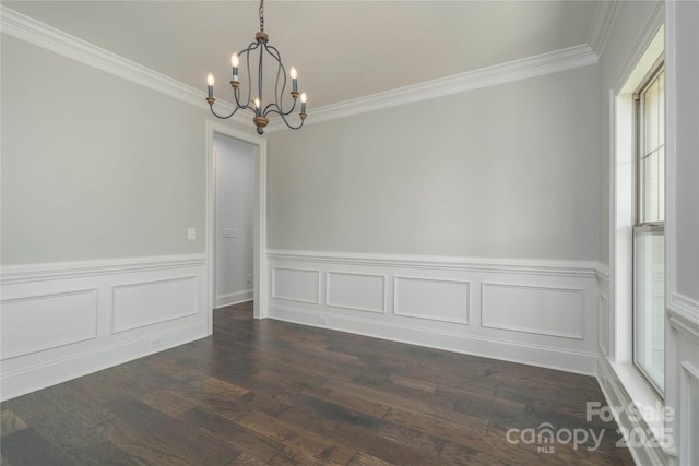 unfurnished dining area featuring wainscoting, an inviting chandelier, crown molding, and dark wood-type flooring