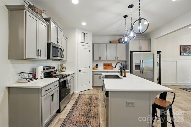 12021 Basking Dr, Charlotte, NC 28214 - kitchen with appliances with stainless steel finishes, gray cabinetry, a sink, a kitchen breakfast bar, and recessed lighting