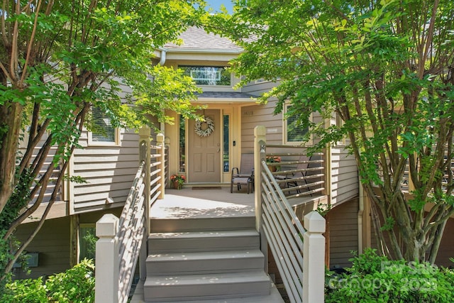 entrance to property featuring roof with shingles