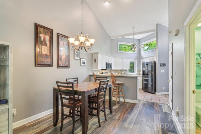 dining space with a notable chandelier, light wood-style floors, baseboards, and high vaulted ceiling