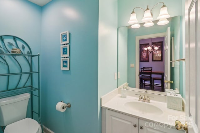 half bathroom with an inviting chandelier, toilet, and vanity