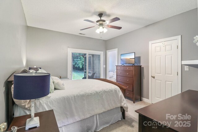 bedroom with light colored carpet, a textured ceiling, visible vents, and a ceiling fan