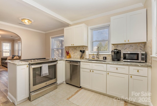3141 Mathis Dr, Charlotte, NC 28208 - kitchen featuring a sink, a peninsula, arched walkways, white cabinets, and appliances with stainless steel finishes