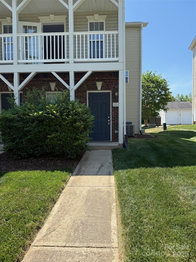 view of front of property with central AC unit, a front yard, and brick siding