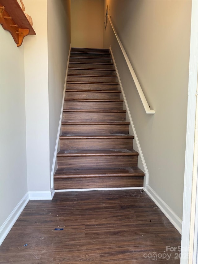 staircase featuring baseboards and wood finished floors