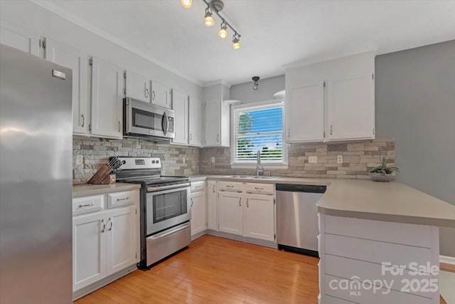 kitchen with stainless steel appliances, a sink, a peninsula, and white cabinets