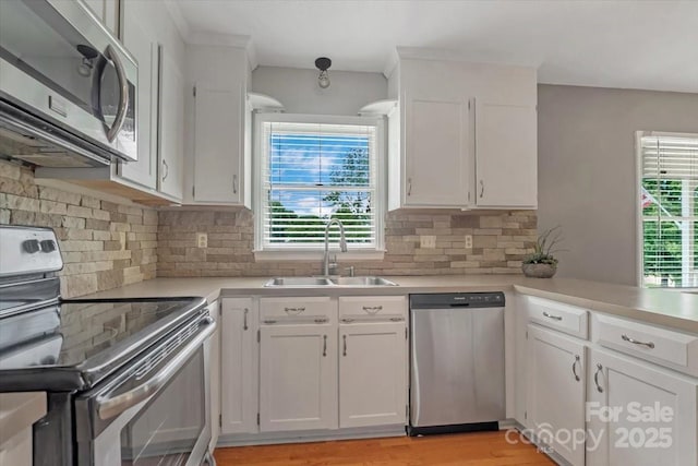 kitchen featuring appliances with stainless steel finishes, a sink, light countertops, and white cabinetry