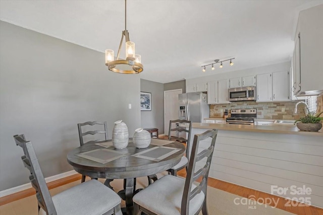 dining area featuring light wood finished floors, a chandelier, and baseboards