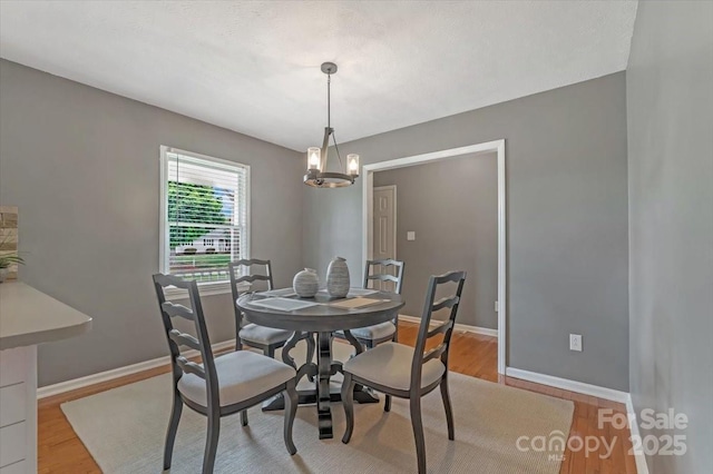 dining space with light wood-type flooring, a chandelier, and baseboards