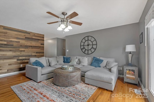 living room with wood finished floors, a ceiling fan, and baseboards