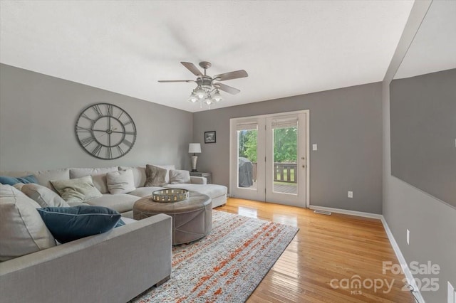 living area featuring ceiling fan, baseboards, and light wood-style floors