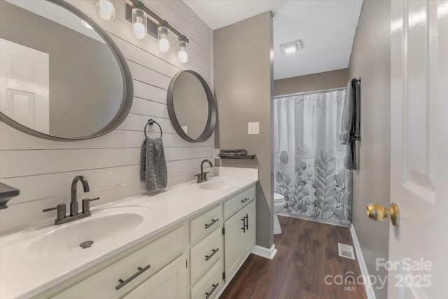 full bath featuring toilet, wood finished floors, double vanity, baseboards, and a shower with shower curtain