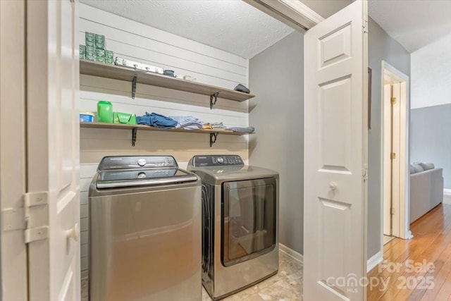 laundry room featuring washer and clothes dryer, baseboards, and light wood-style flooring
