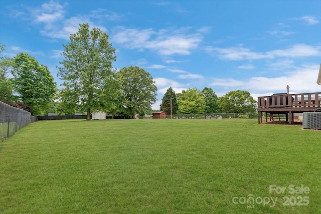 view of yard with central AC, a deck, and a shed