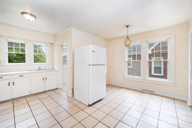 813 S Ridge Ave, Kannapolis, NC 28083 - kitchen with freestanding refrigerator, a sink, light countertops, white cabinets, and hanging light fixtures