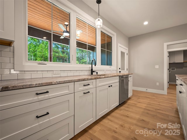 109 Ashley Ct, Mill Spring, NC 28756 - kitchen with stainless steel dishwasher, a sink, backsplash, light wood-style floors, and baseboards