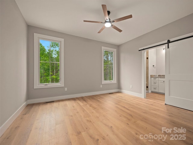 109 Ashley Ct, Mill Spring, NC 28756 - unfurnished bedroom featuring a barn door, light wood-style floors, baseboards, and ensuite bath