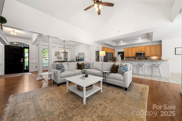 living area featuring light wood finished floors, a ceiling fan, ornamental molding, a chandelier, and a raised ceiling