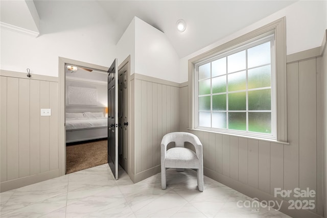bathroom featuring marble finish floors, lofted ceiling, a wainscoted wall, connected bathroom, and a decorative wall